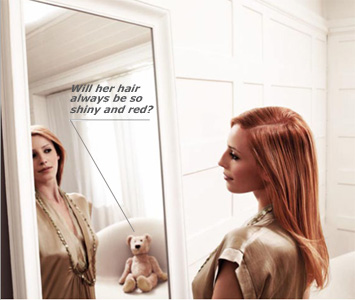 Red-headed model looking at herself in mirror with on-looking teddy bear, thinking - Will her hair always look so shing and red?